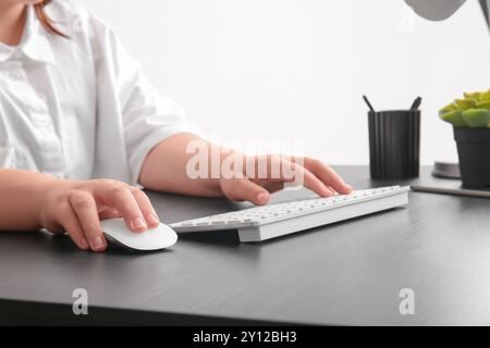 Female programmer using computer keyboard and mouse on table in office Stock Photo