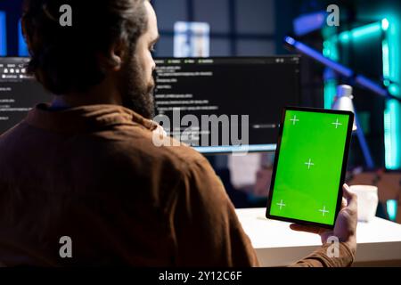 Programmer designing and developing software applications using green screen tablet. IT administrator implementing and maintaining company systems using chroma key device Stock Photo