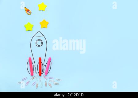 Creative composition with drawn rocket and different stationery on blue background Stock Photo