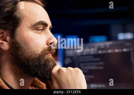 Freelancing programmer working from home, designing and developing software applications. IT specialist looking at desktop PC monitor, implementing and maintaining company systems, close up Stock Photo