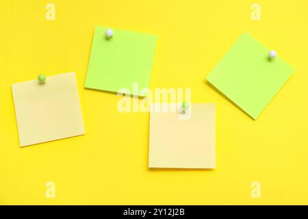 Paper notes pinned on yellow background Stock Photo