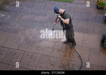 A man cleaning a patio in a garden or backyard with a pressure washer Stock Photo