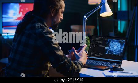 Data scientist updating artificial intelligence neural networks, writing complex binary code scripts. Teleworking freelancer in apartment office uses digital device programming to upgrade AI, camera A Stock Photo