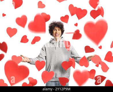 Young man standing under red falling hearts isolated on white background Stock Photo