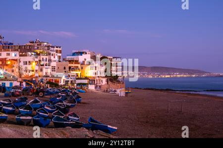 Taghazout, small fishing and surfing village with sandy beach, boats and traditional Moroccan buildings near Agadir, Morocco at sunset. Popular Stock Photo