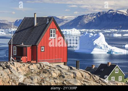 Typical Greenlandic houses in front of icebergs, Inuit settlement, summer, sunny, Uummannaq, West Greenland, Greenland, North America Stock Photo