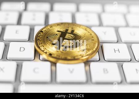 Bitcoin coin lying on white computer keyboard Stock Photo