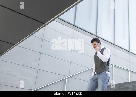 Young and Casual Businessman Using Smartphone while Walking Outside of Office Building Stock Photo