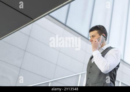 Young and Casual Businessman Using Smartphone while Walking Outside of Office Building Stock Photo