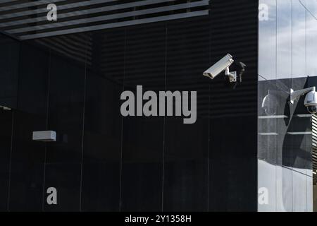 Photo of Modern CCTV camera on a wall. A blurred night cityscape background. Concept of surveillance and monitoring. Toned image double exposure mock Stock Photo