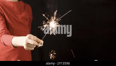Child holding burning firework sparkler, celebrating Christmas and new year Stock Photo