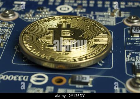 Photo of A single Bitcoin coin on the blue computer motherboard Stock Photo