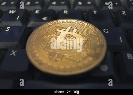 Golden Bitcoin coin lying on a black computer keyboard. Digital money concept Stock Photo