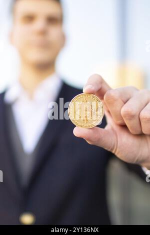 Bitcoin cryptocurrency coin in a young businessman hand. Disruptive blockchain technology concept and transfer of wealth Stock Photo