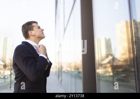 Young businessman looking himself in the glass mirror and adjusting collar. Preparation for job interview for business deal Stock Photo