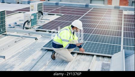 Engineering, man and tablet for solar panels, energy saving and electricity or heating of eco friendly grid on rooftop. Technician, digital technology Stock Photo