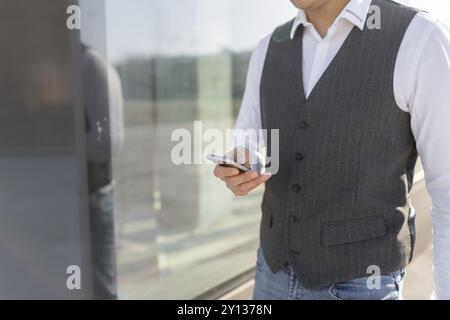 Young and Casual Businessman Using Smartphone while Walking Outside of Office Building Stock Photo