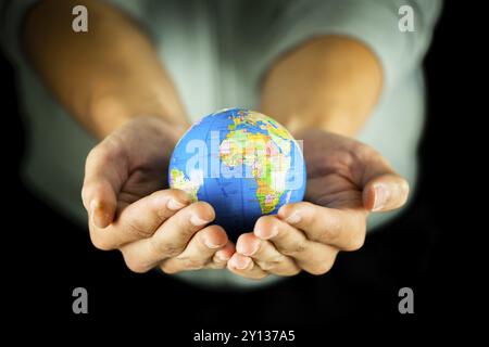 Male hands holding the Earth globe on black background Stock Photo