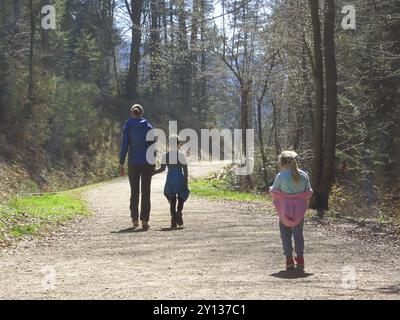 Mother with son and daughter hiking and having fun and beeing happy together and holding hands. Family trip in a forest at spring Stock Photo