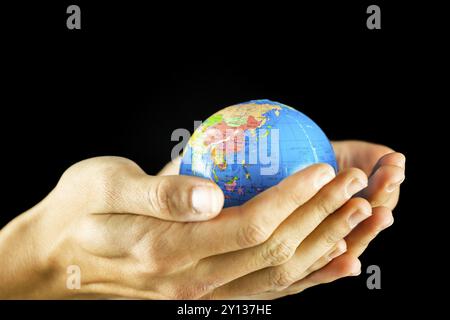 Male hands holding the Earth globe on black background Stock Photo