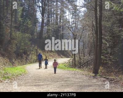 Mother with son and daughter hiking and having fun and beeing happy together and holding hands. Family trip in a forest at spring Stock Photo