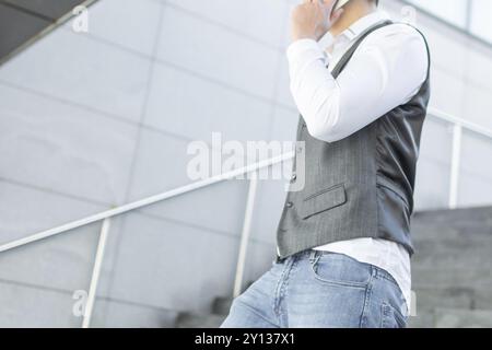 Young and Casual Businessman Using Smartphone while Walking Outside of Office Building Stock Photo