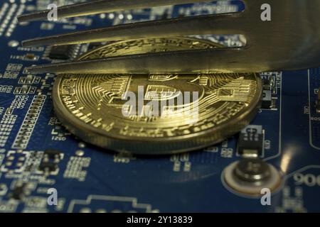 Photo of A single Bitcoin coin on the blue computer motherboard Stock Photo