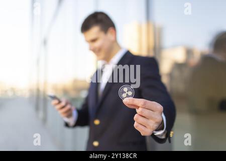 Ripple cryptocurrency coin in a young businessman hand. Disruptive blockchain technology concept and transfer of wealth Stock Photo