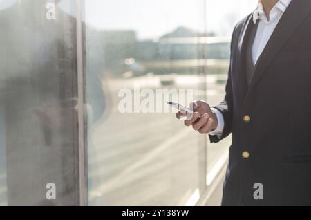 Young and Casual Businessman Using Smartphone while Walking Outside of Office Building Stock Photo