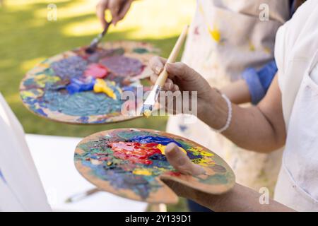 Painting on canvas, people holding palettes and brushes, creating colorful artwork Stock Photo