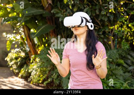Using VR headset, asian woman exploring virtual reality outdoors in garden Stock Photo