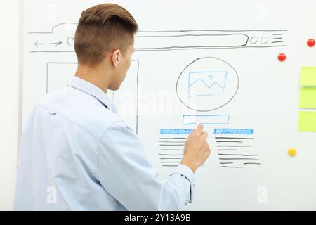 Developing UI design. Man drawing website wireframe on whiteboard indoors Stock Photo