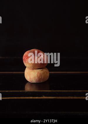 Minimal Still Life: Two Fig Peaches Stacked on a Black Piano Stock Photo