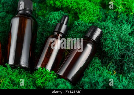 Brown glass dropper bottles arranged on green moss in a natural setting Stock Photo