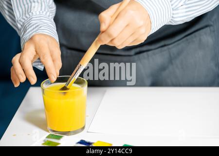 Artist rinsing out paintbrush with water in glass, close up Stock Photo
