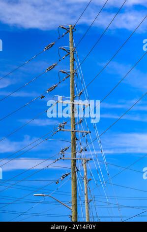 Toronto, Canada - September 2, 2024: A wooden electric pole with multiple cables against a clear blue sky. Stock Photo