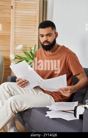 Man attentively studies papers while seated comfortably at home. Stock Photo