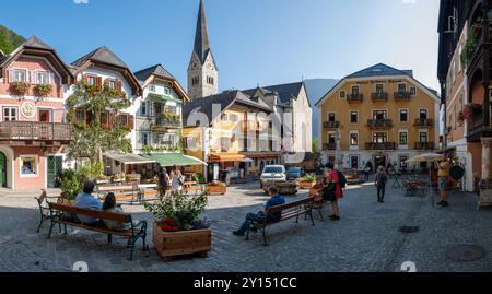 Hallstatt Austria 25 August 2024, The vibrant village square in Hallstatt comes alive with locals and visitors enjoying the beautiful weather. Colorful buildings surround the cobblestone area Stock Photo