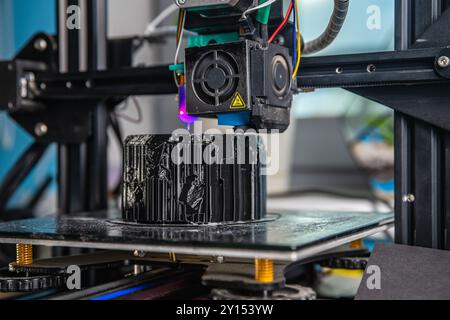A 3D printer prints a black model. Technology at home Stock Photo