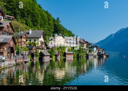 Nestled between lush mountains, the charming village of Hallstatt features picturesque wooden houses reflecting on the calm waters of the lake, creating a tranquil and idyllic atmosphere. Stock Photo