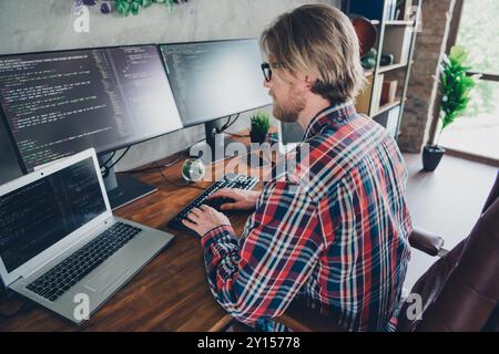 Photo of young senior level it specialist programmer man blond hair wearing eyeglasses and checkered shirt sitting workplace using computer Stock Photo