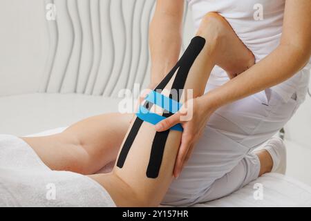 Kinesio taping of the lower extremities to prolong the massage effect close-up, the therapist applies tape to the patient's legs Stock Photo