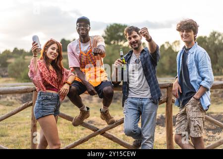 Group of diverse young adults celebrating and socializing outdoors. Multicultural friends enjoying drinks and nature, showcasing inclusivity and joyfu Stock Photo