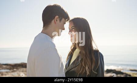 A serene couple enjoys an intimate moment together at the seaside, with the ocean's vast expanse behind them. Stock Photo