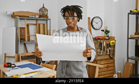 African woman carpenter reviewing plans in a workshop Stock Photo