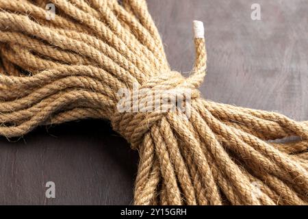 Knotted bundle of rough jute rope on brown board in close up. Stock Photo