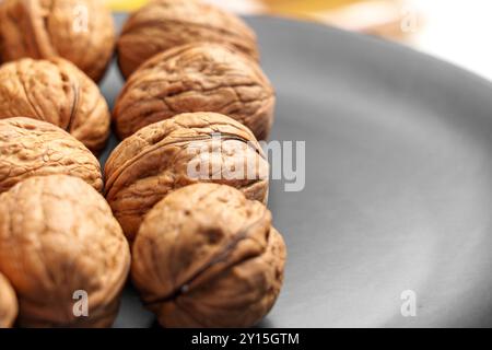 Freshly harvested walnuts gathered from the orchard on a black ceramic plate close up Stock Photo