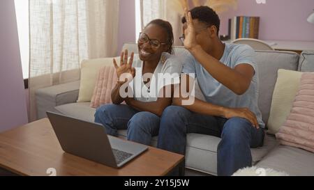 Mother and son making a video call at home while sitting on a couch in the living room, showing love and family connection in an indoor setting Stock Photo