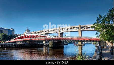 Panoramic view of red and white swing bridge over a river with a stone arch high level bridge in the background in newcastle upon tyne Stock Photo