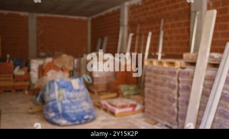 Blurred background of unfinished construction site with bricks cement bags and scaffolding materials Stock Photo